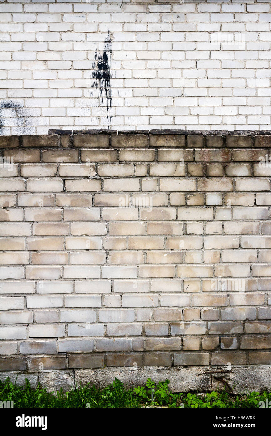 Old weathered wall of bricks with a splash of black tar Stock Photo