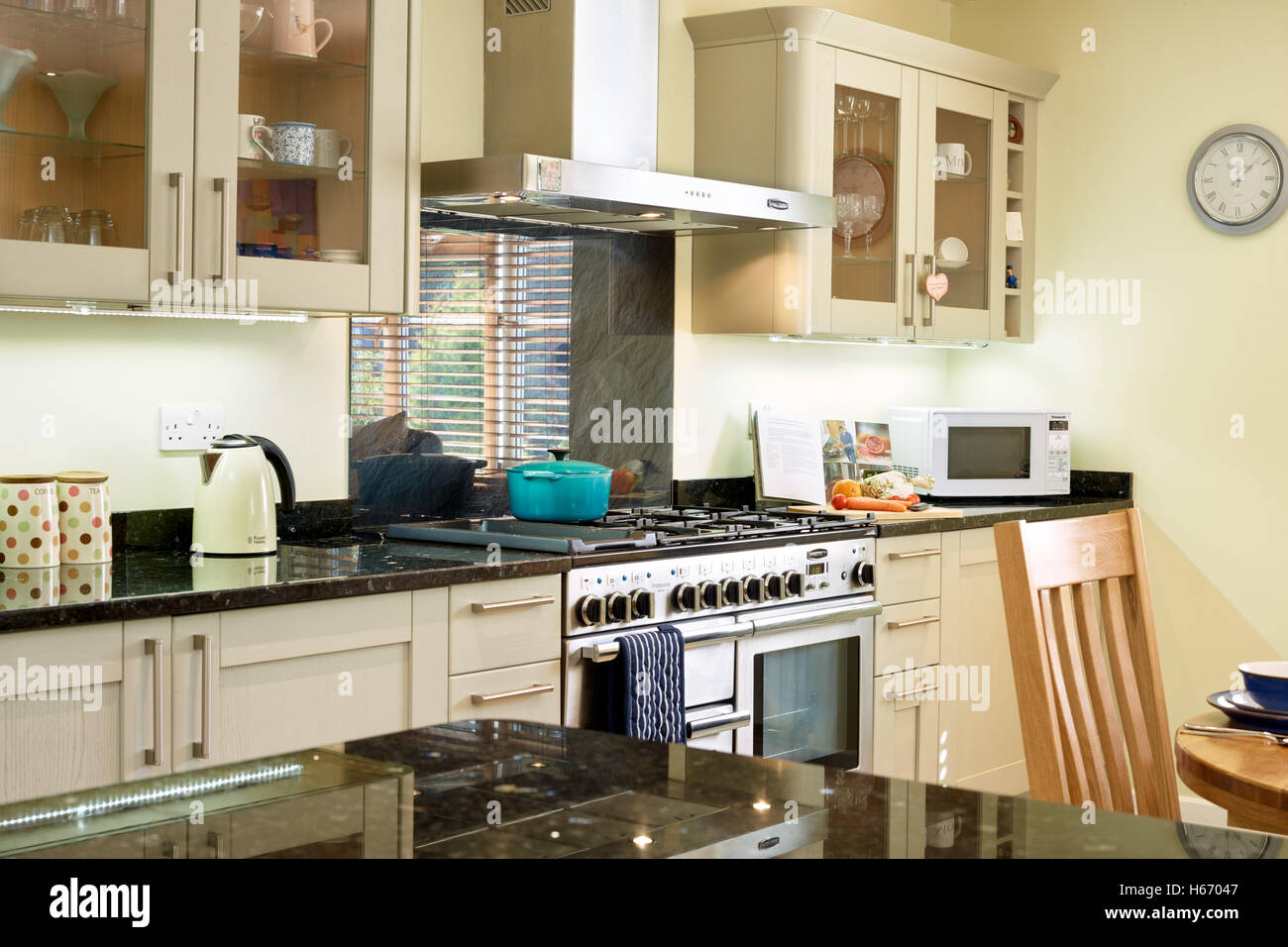A contemporary open plan kitchen incorporating a range cooker, hood & granite work surfaces. Oxfordshire, UK Stock Photo