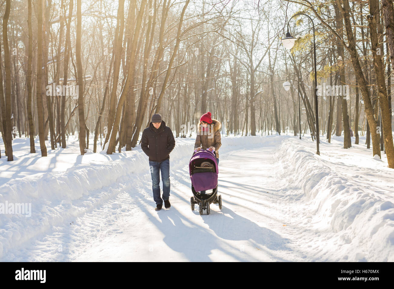 Happy young family walking in the park in winter. The parents carry the ...