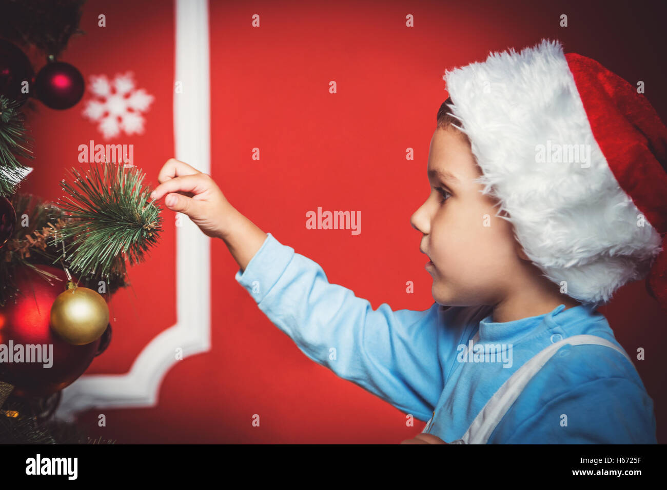 beautiful portrait of little boy in Santa hat decorating the Christmas tree new year room. The idea for postcards. Soft focus. S Stock Photo