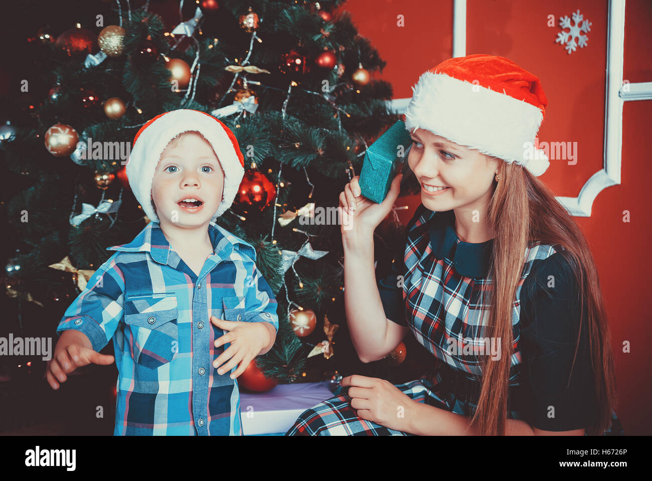 beautiful portrait of happy mother and son on the background of the Christmas tree in new year room with gifts. The idea for pos Stock Photo