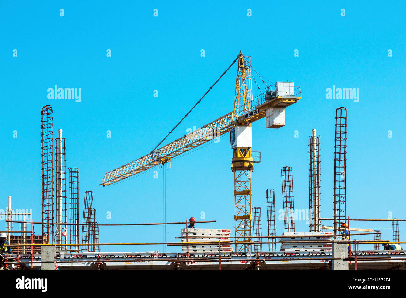 High lift crane and many unknown people working amongst scaffolding and