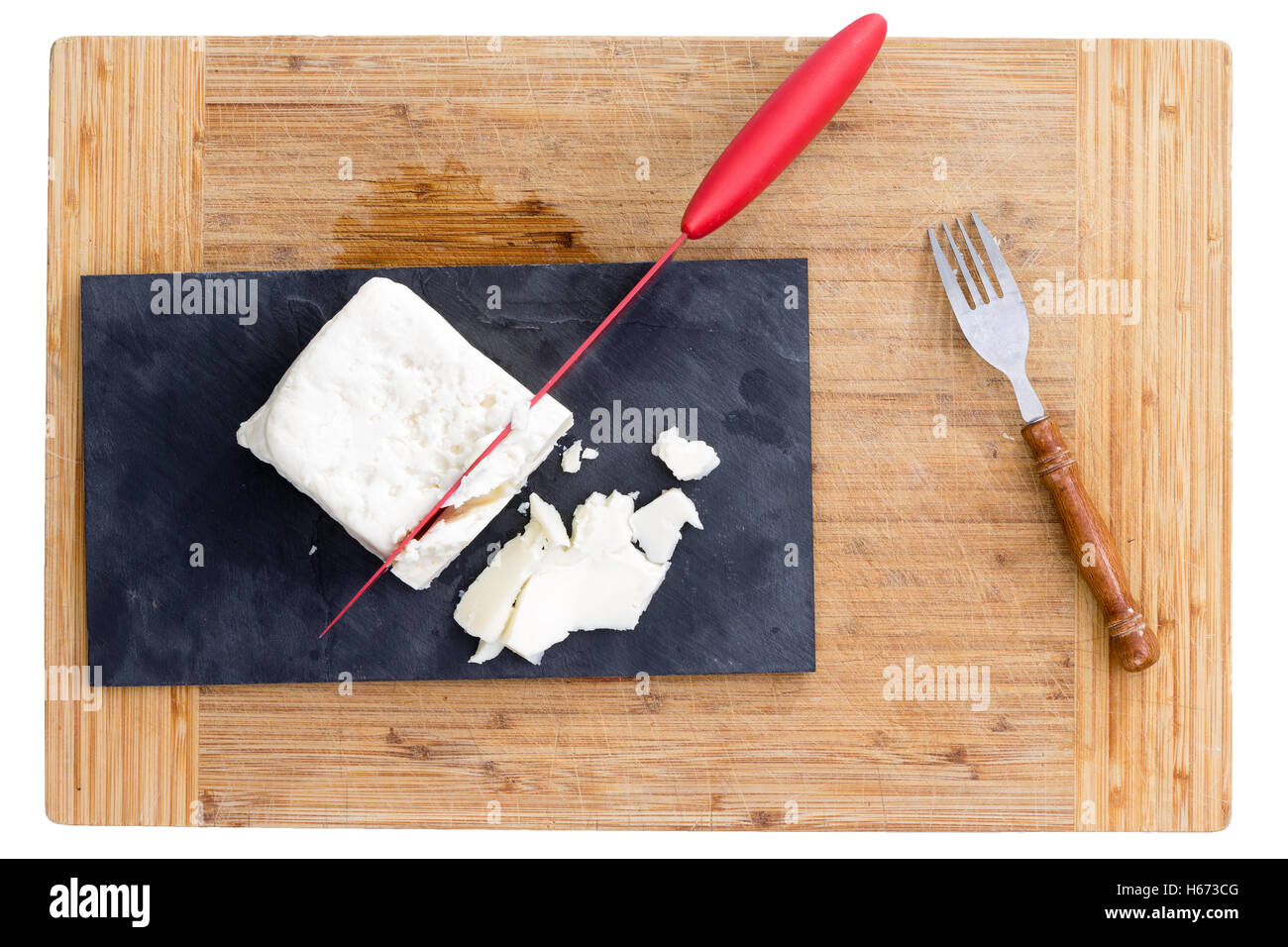 Top down view of red knife cutting white feta cheese on purple paper ...
