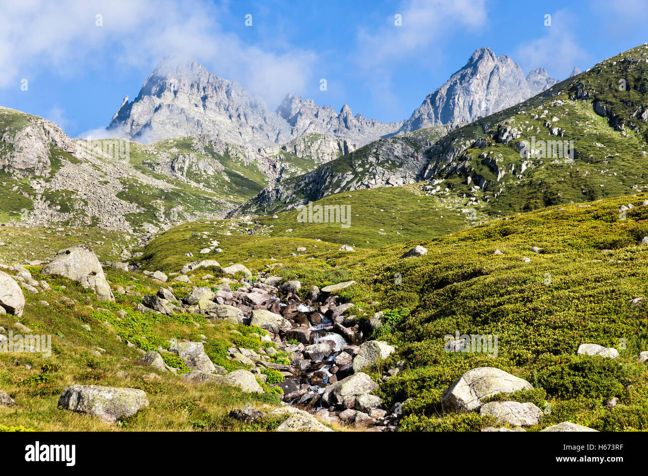 Stream flowing between the rocks with foggy Kackar mountains peak background Stock Photo