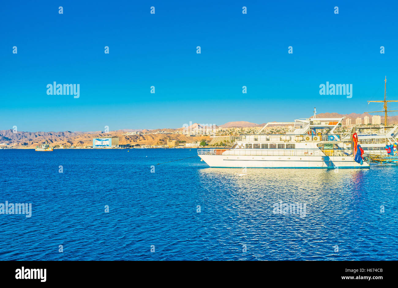 The snow-white pleasure boats in harbor with the mountain coast on the background, Eilat, Israel. Stock Photo