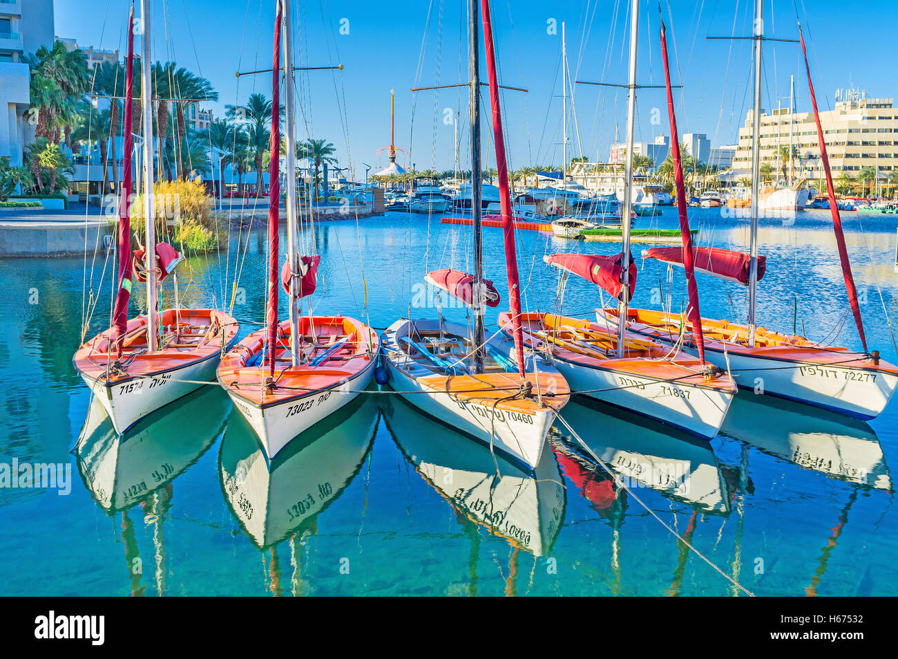 The sailing yachts in bright sun beams with the clear reflection in water, Eilat Stock Photo