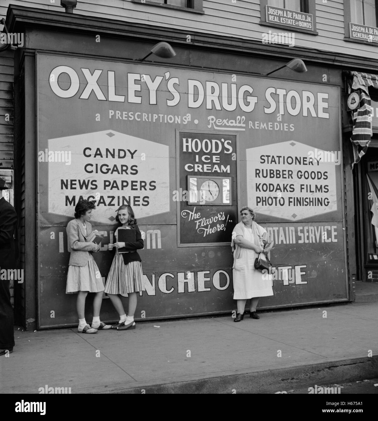 Two High School Girls and Woman Standing in front of Large Store Sign, Southington, Connecticut, USA, Fenno Jacobs for Office of War Information, May 1942 Stock Photo