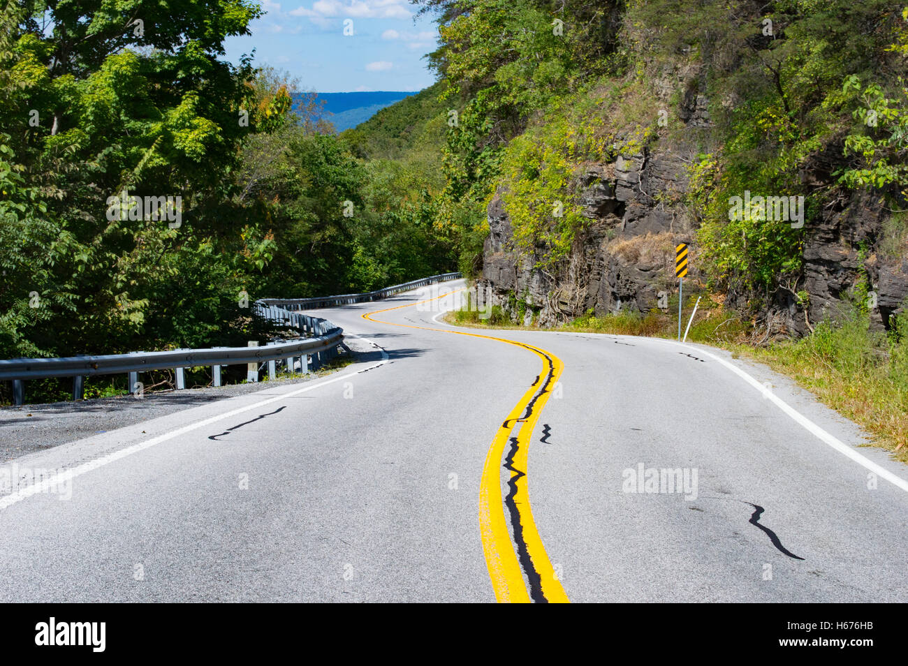 Mountain road with scenic panorama in the background. Left half of the picture contains rocky outcrop of the Appalachian mountain Stock Photo