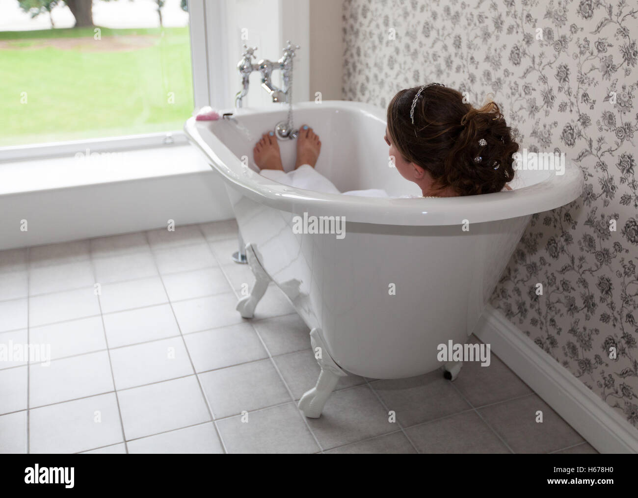 Bride laid in the bath on her wedding day, taking a moment to herself. Stock Photo