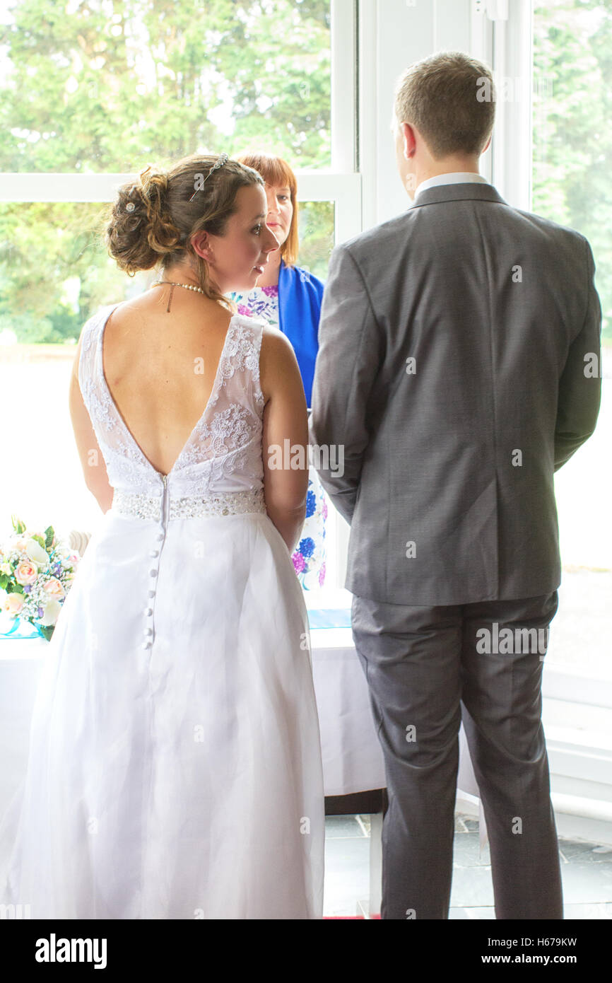 Bride and groom during their wedding ceremony, taken in vertical format from behind them. Stock Photo