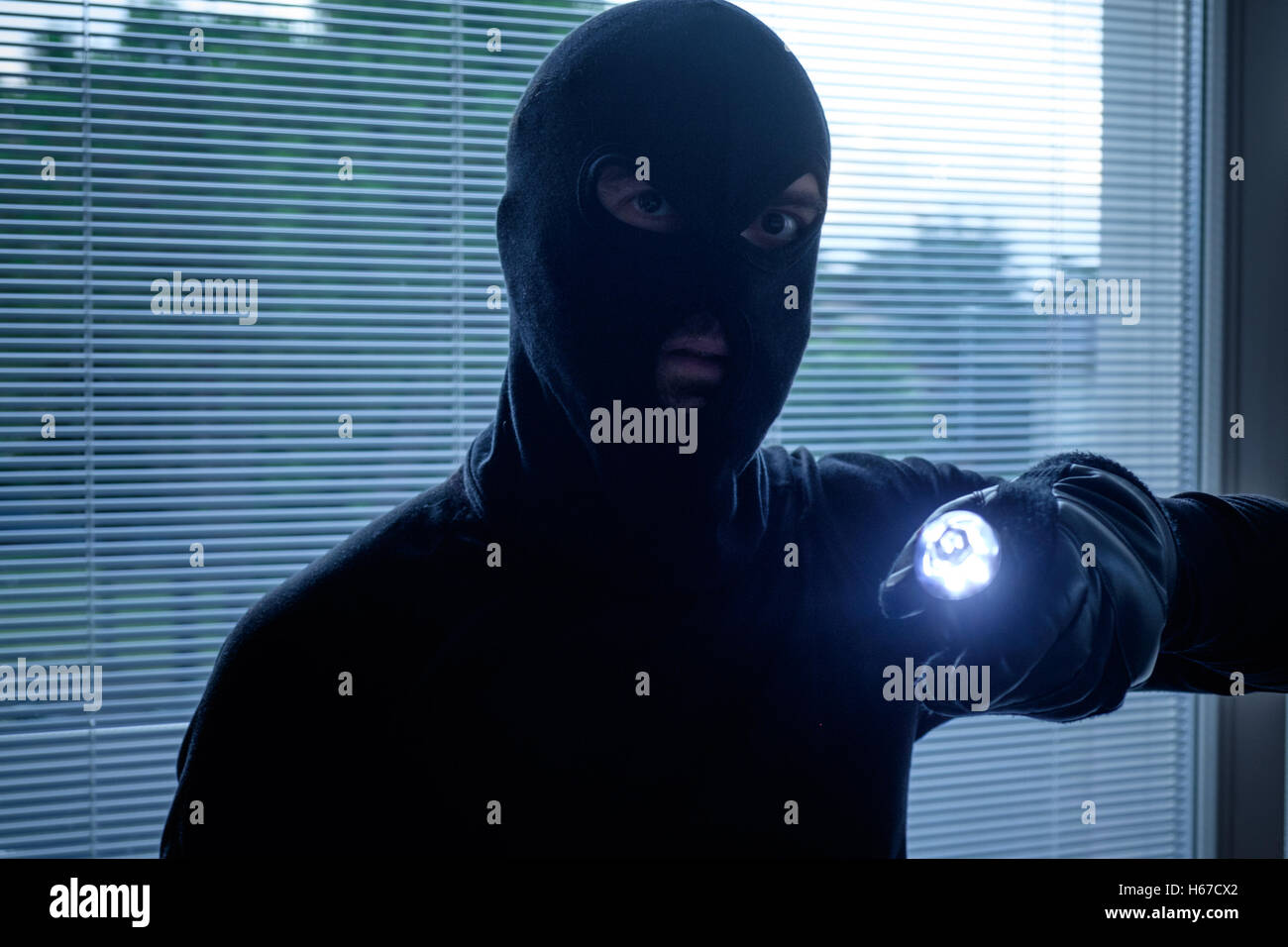 Burglar wearing a balaclava holding a flashlight Stock Photo