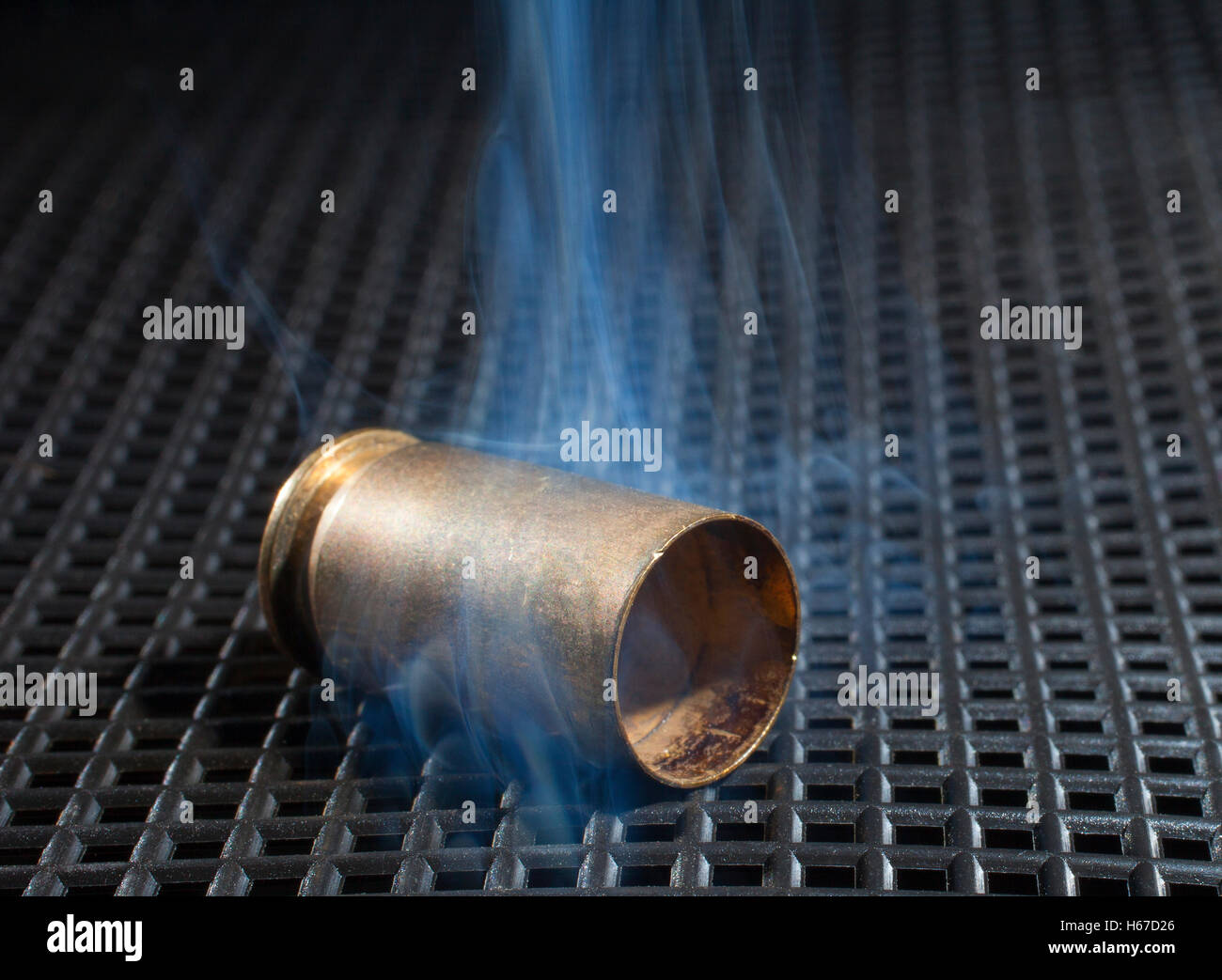 Empty handgun brass with smoke on a black grate Stock Photo Alamy