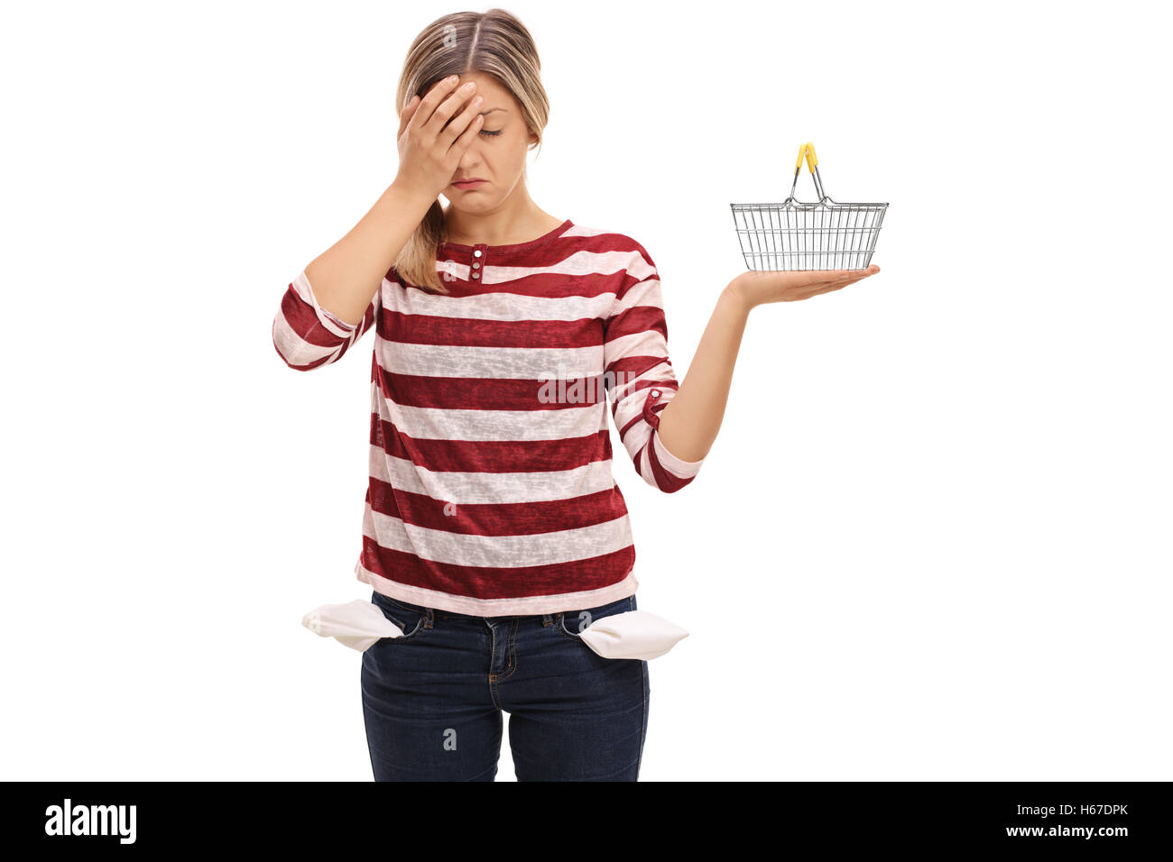 Young woman with empty pockets holding her head in disbelief and holding a small empty shopping basket Stock Photo