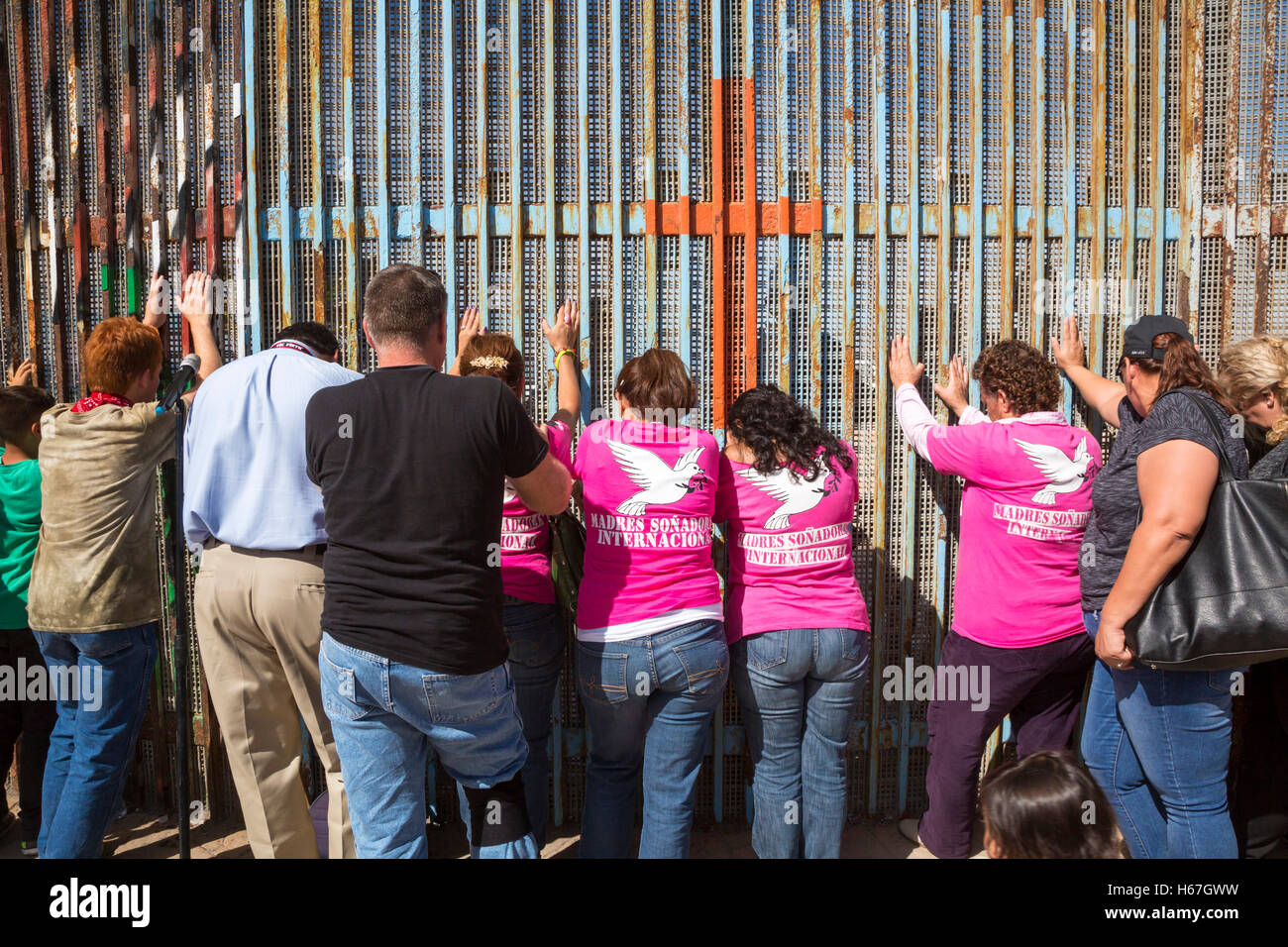 Tijuana, Mexico - People pray during Sunday interfaith worship at the U.S.-Mexico border fence. Stock Photo