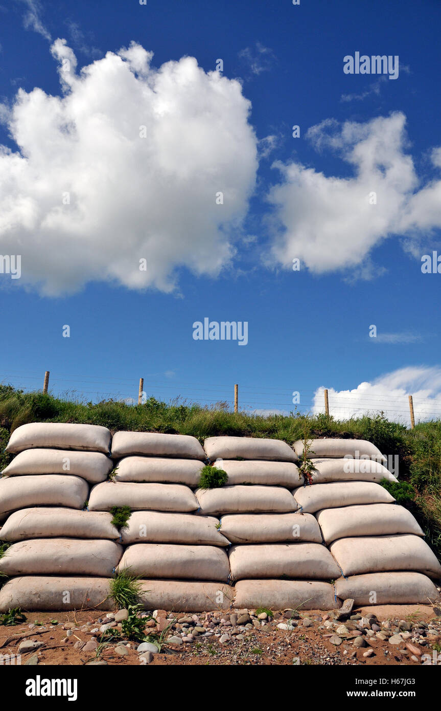 A pile of sandbags lined against a stretch of coastal embankment at risk of coastal erosion. Stock Photo