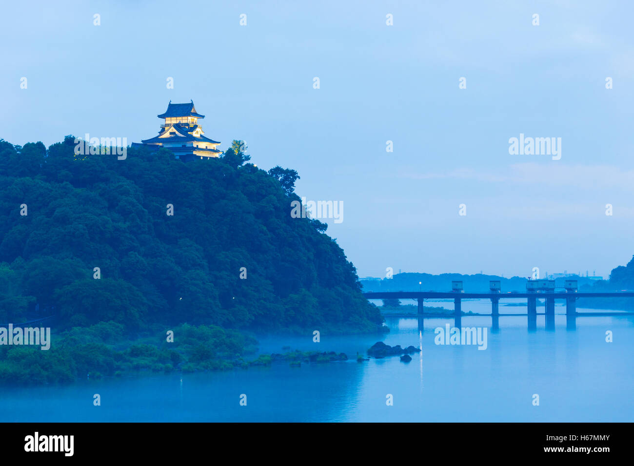 Evening on the Kiso River from distant Inuyama Castle atop a forest hill at blue hour in Gifu Prefecture, Japan. Horizontal Stock Photo