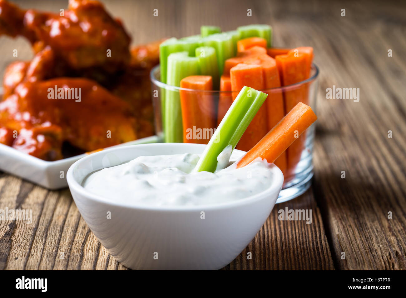 Blue cheese dressing for dipping served with celery sticks, carrot sticks and buffalo chicken wing with cayenne pepper  sauce Stock Photo