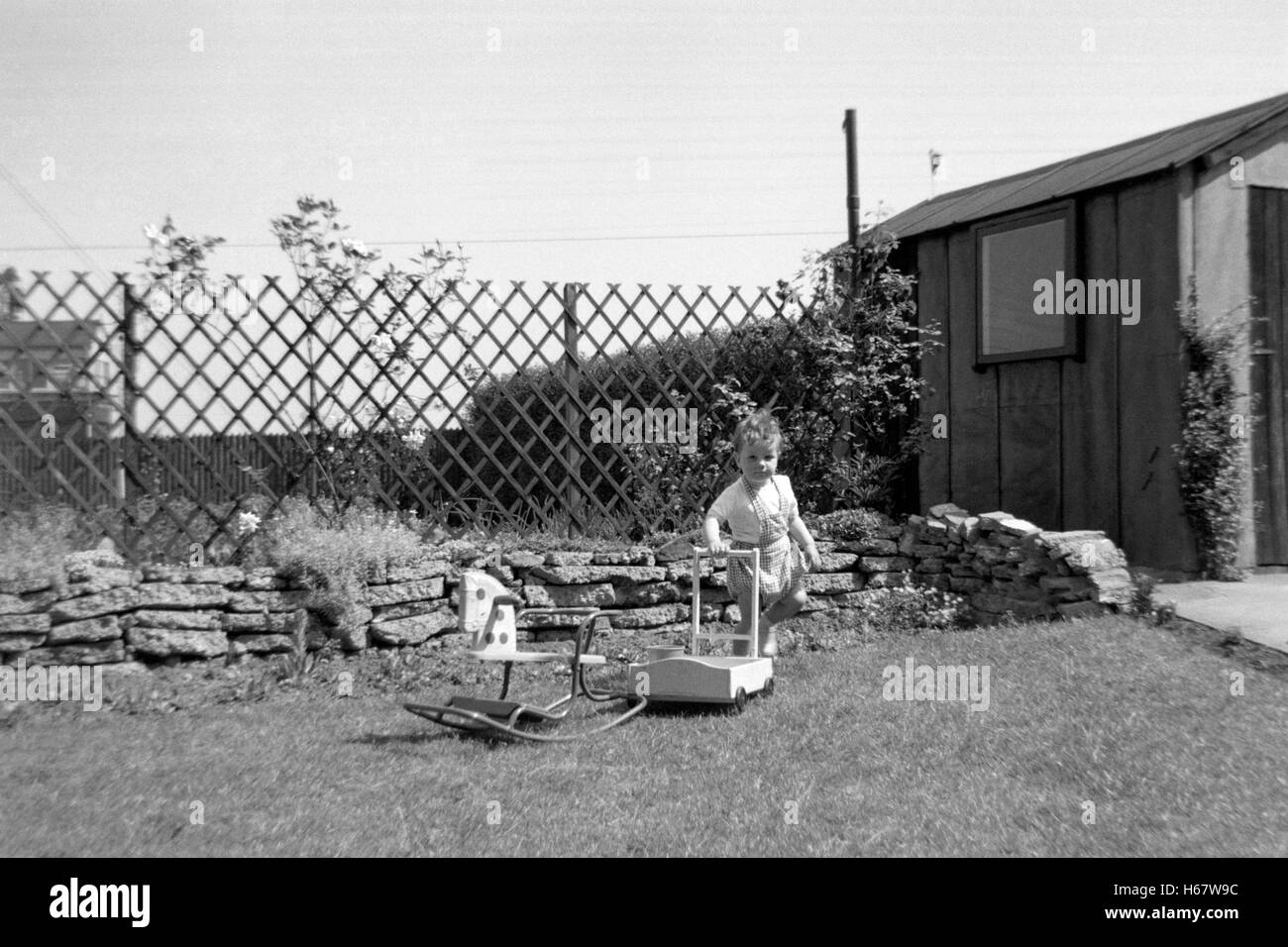 young boy playing in garden with rocking horse and truck england uk 1950s Stock Photo