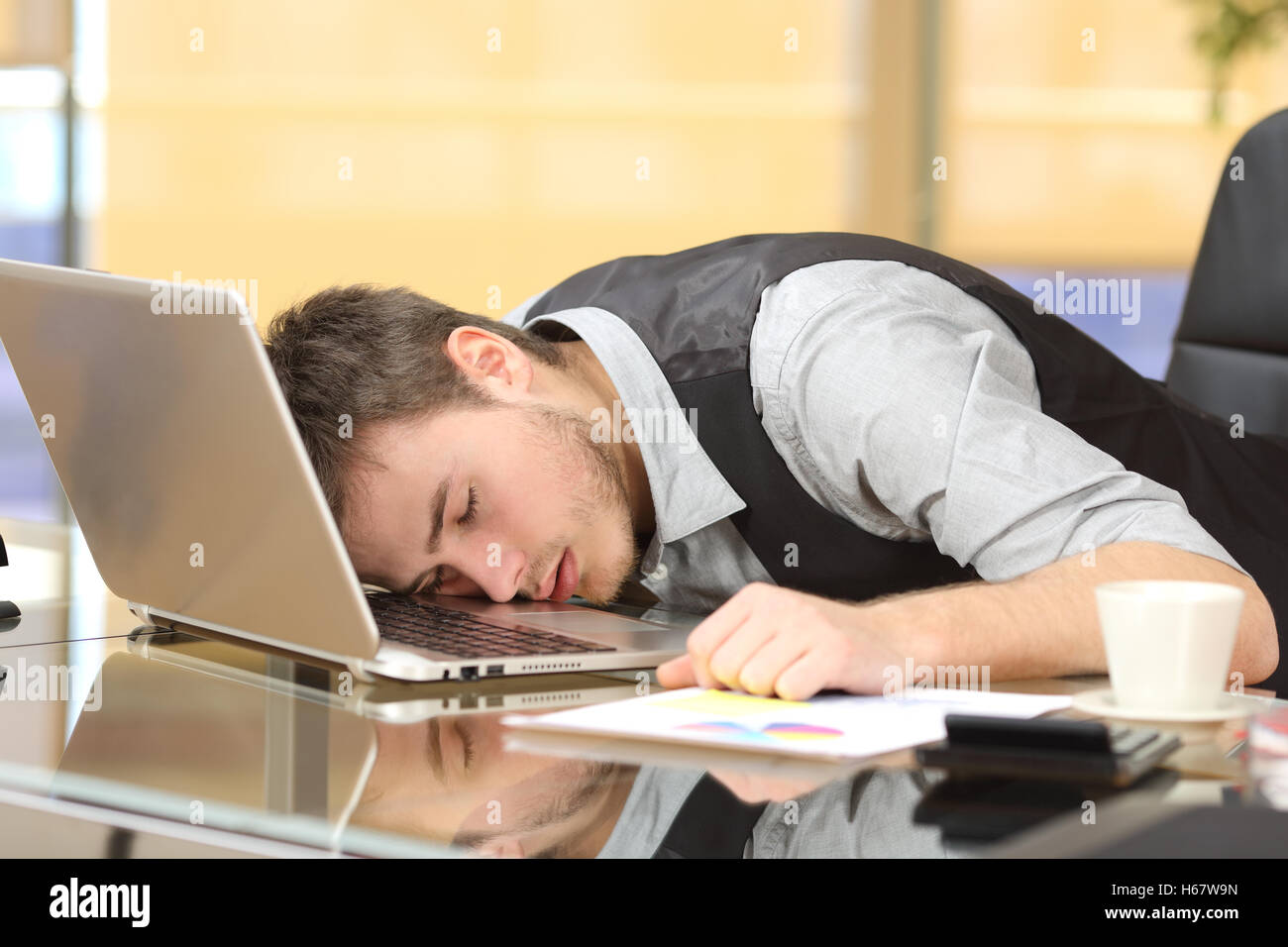 Tired overworked businessman sleeping over a laptop in a desk at job in