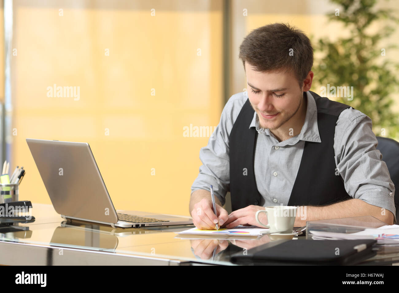Young businessman working writing notes sitting in a desktop at office Stock Photo