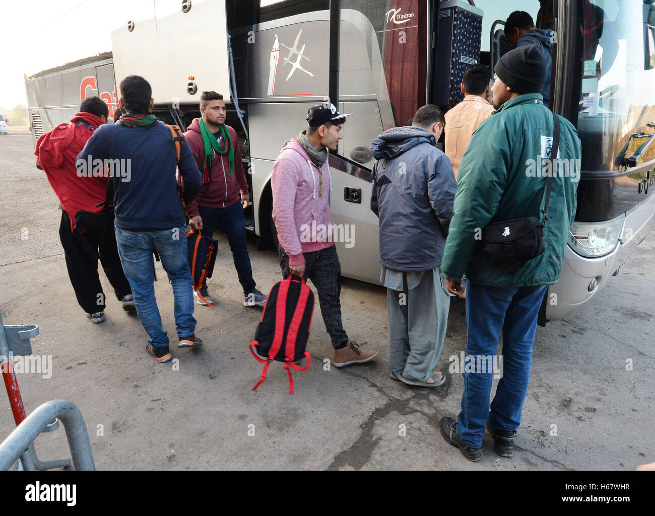 Migrants board a bus from a processing centre in 'the jungle' near Calais, northern France, as the mass exodus from the migrant camp continues. Stock Photo