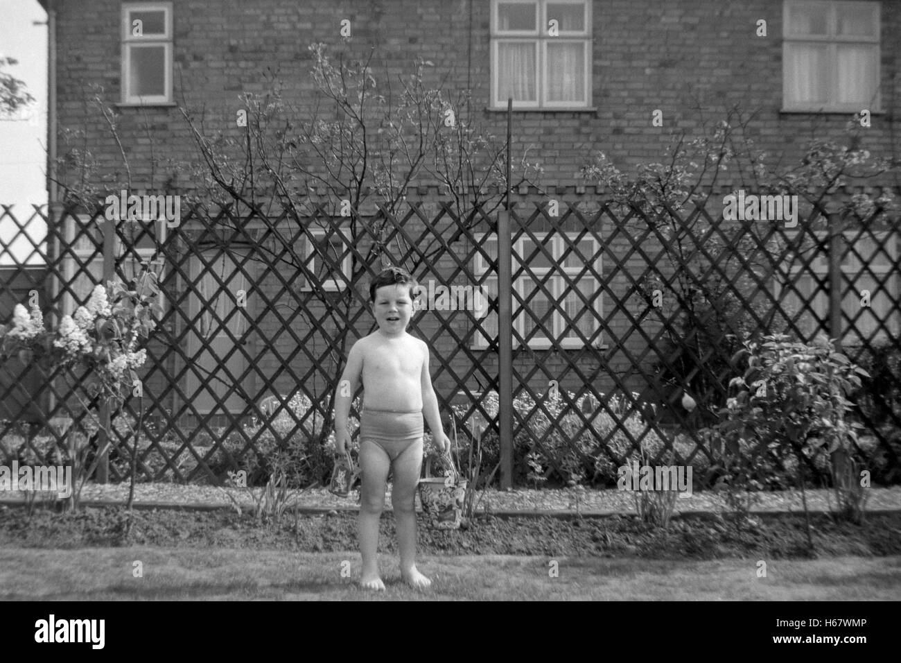 young boy playing in garden with buckets uk 1950s Stock Photo