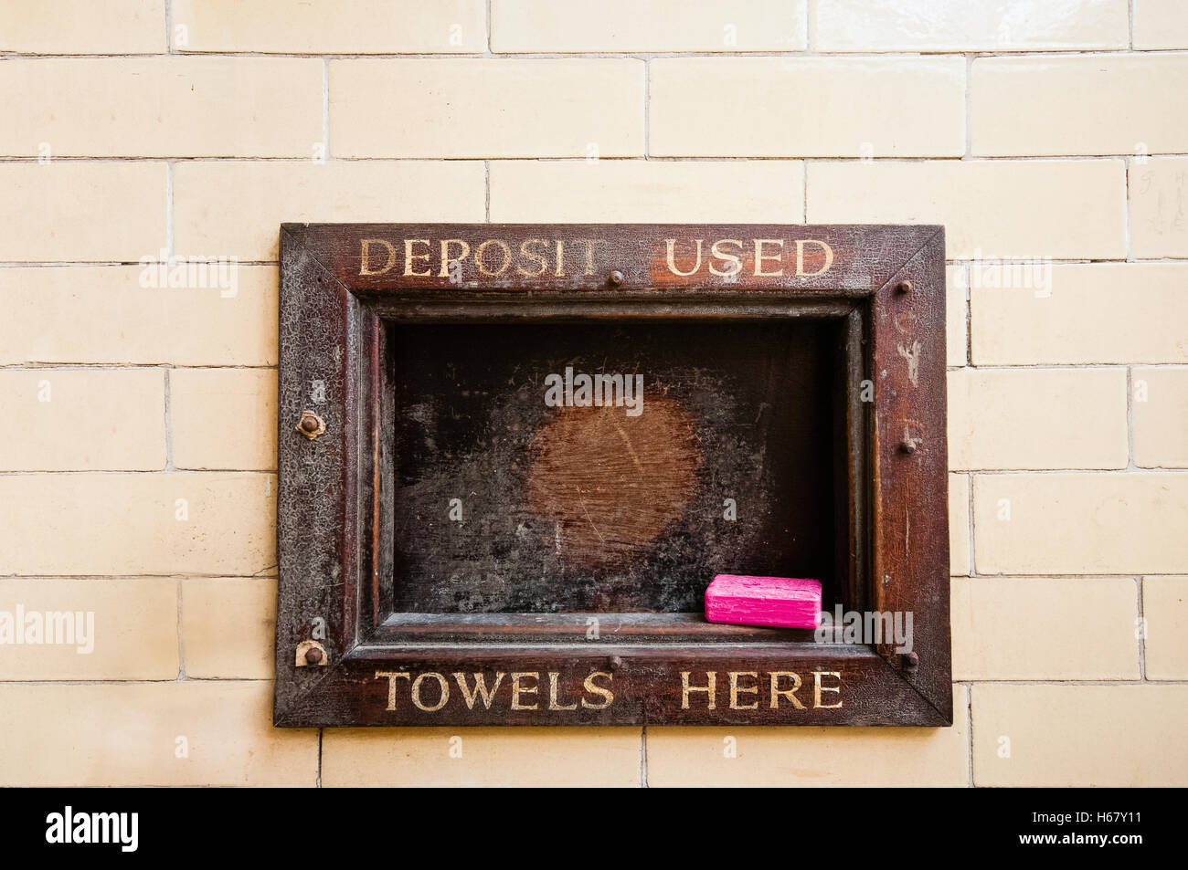 Wooden hatch at an old Victorian public baths swimming pool "deposit used towels here" with a bar of red carbolic soap. Stock Photo