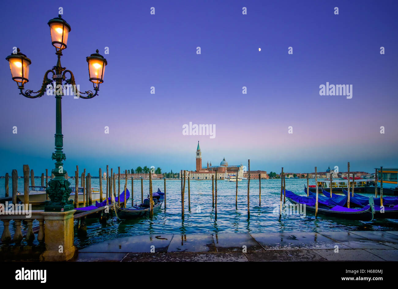Venice, street lamp and gondolas or gondole on a blue sunset twilight and San Giorgio Maggiore church landmark on background. It Stock Photo