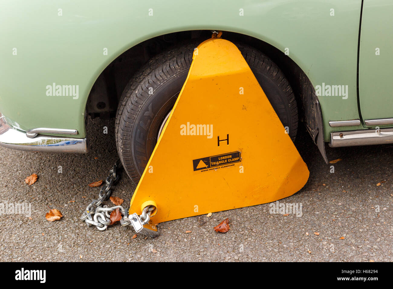 Nissan Figaro classic car with yellow triangle wheel parking clamp attached. Stock Photo