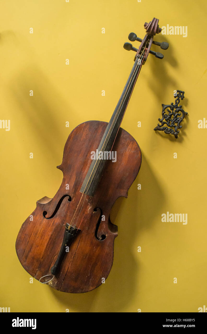 Old worn vintage cello hanging on yellow wall Stock Photo Alamy