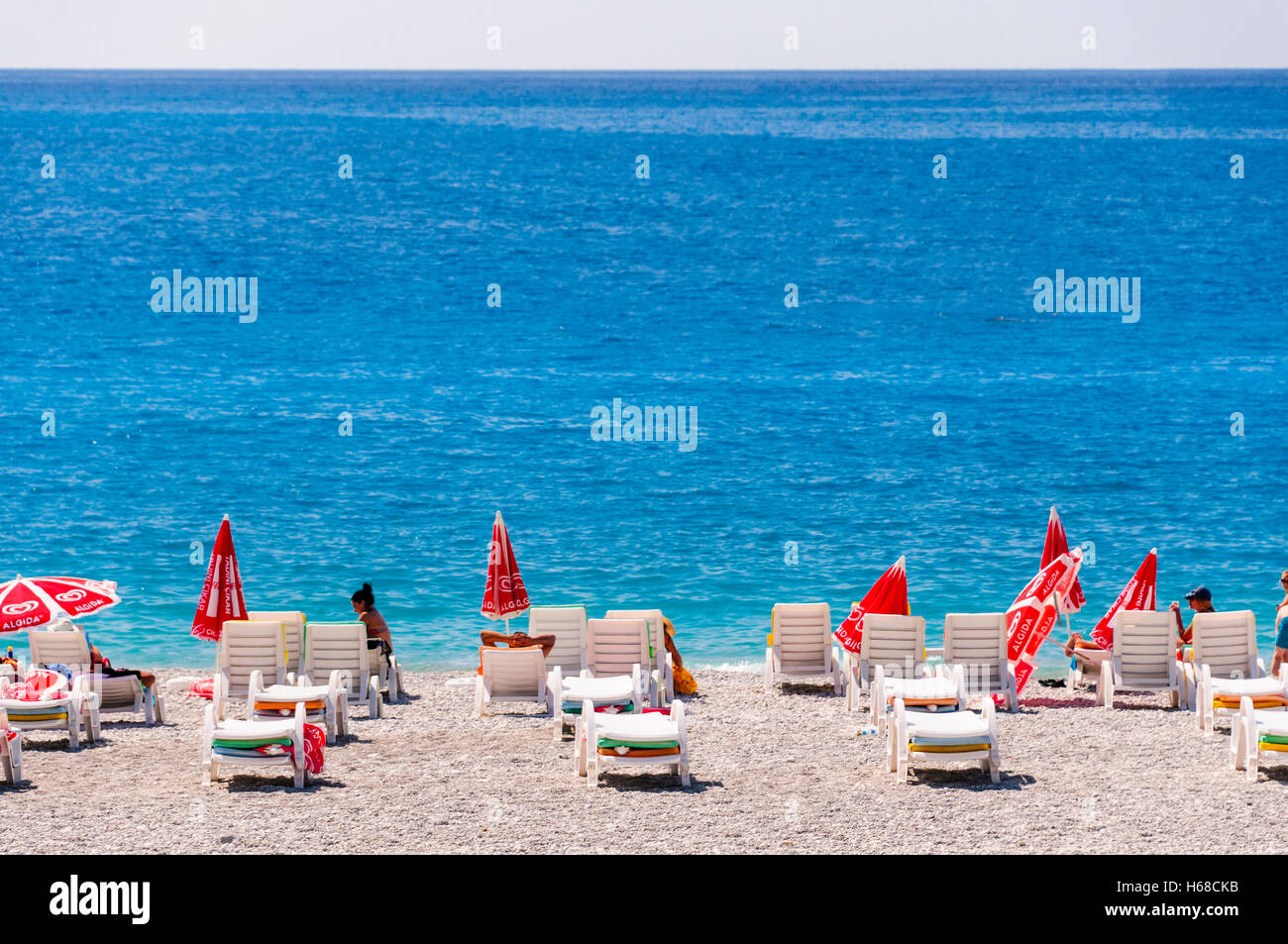 Sunloungers and umbrellas on a beach in front of a blue sea. Stock Photo