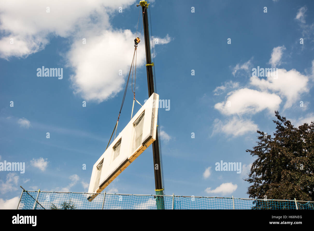 Assembling a prefabricated house - wall is hanging on a crane Stock Photo