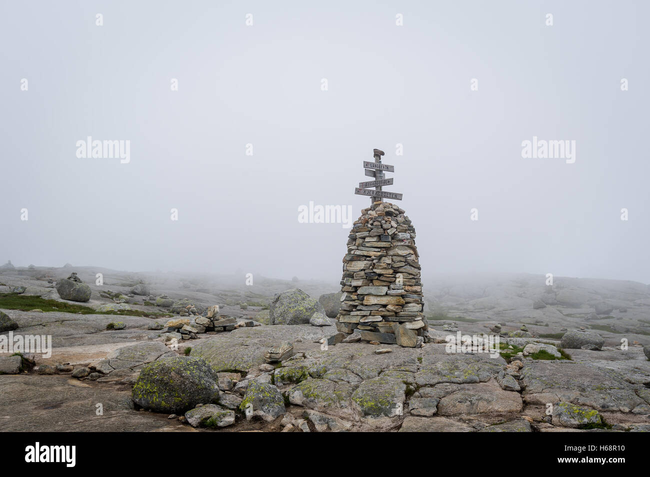 Stone pyramide with hiking path route sign in the foggy weather. Stock Photo