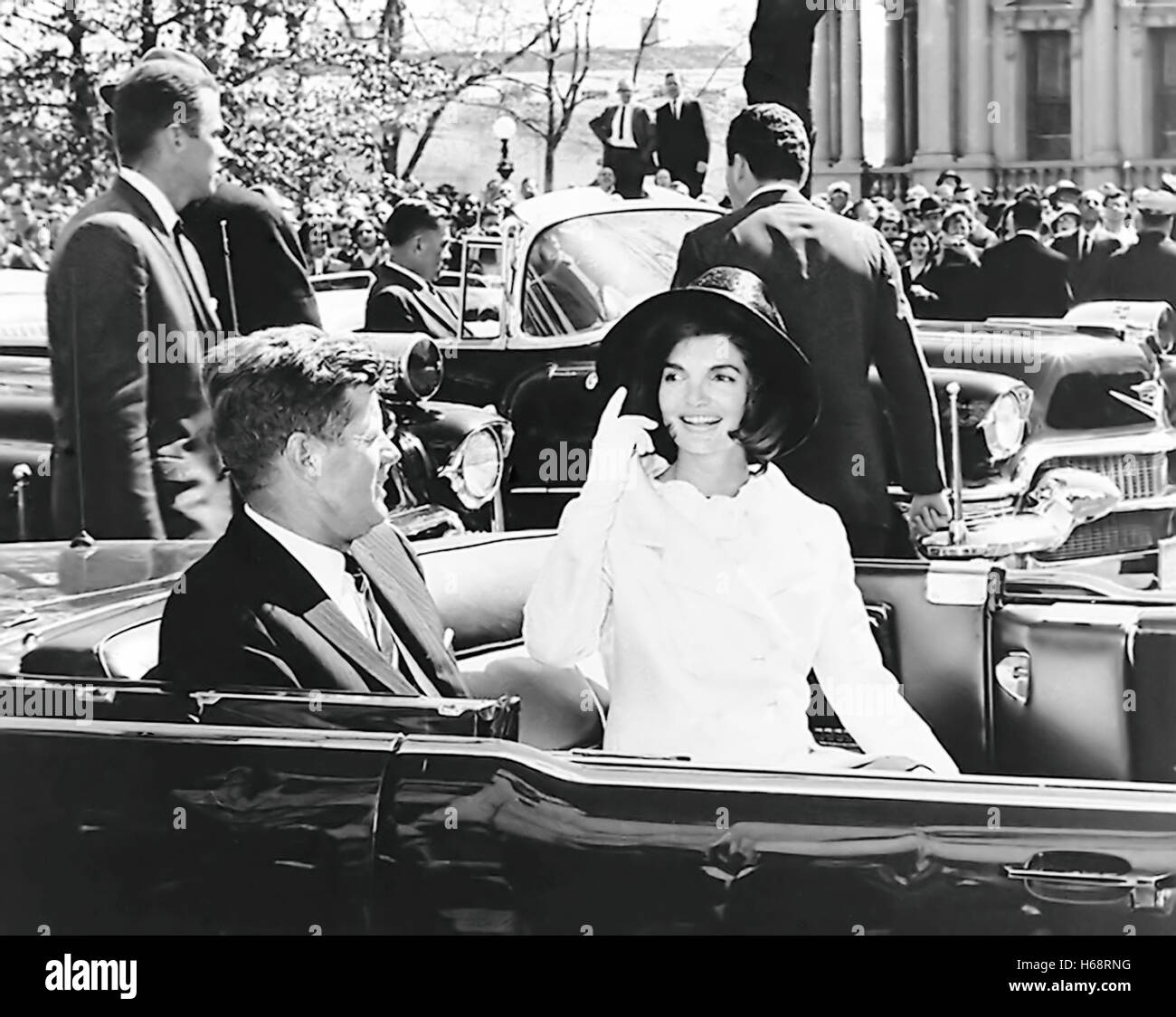 President John F. Kennedy and Jacqueline Kennedy in open top presidential limousine leaving the White House. Stock Photo