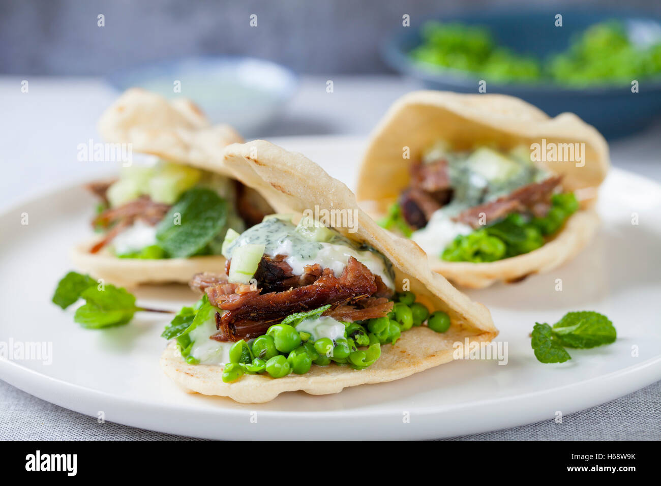 Mini flat breads with crispy lamb, mashed peas, cucumber, mint and yogurt sauce Stock Photo