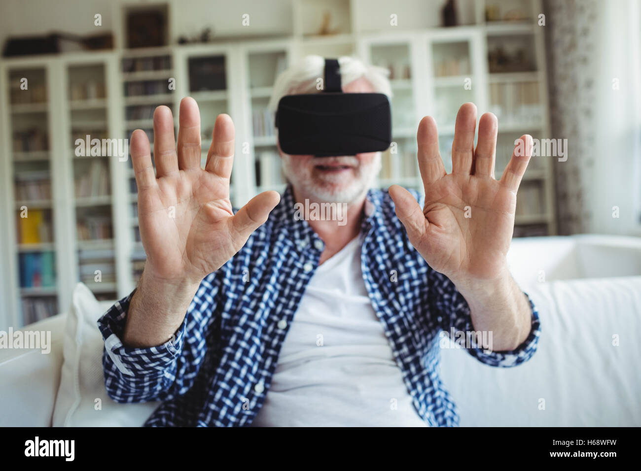 Senior man wearing virtual reality headset in living room Stock Photo