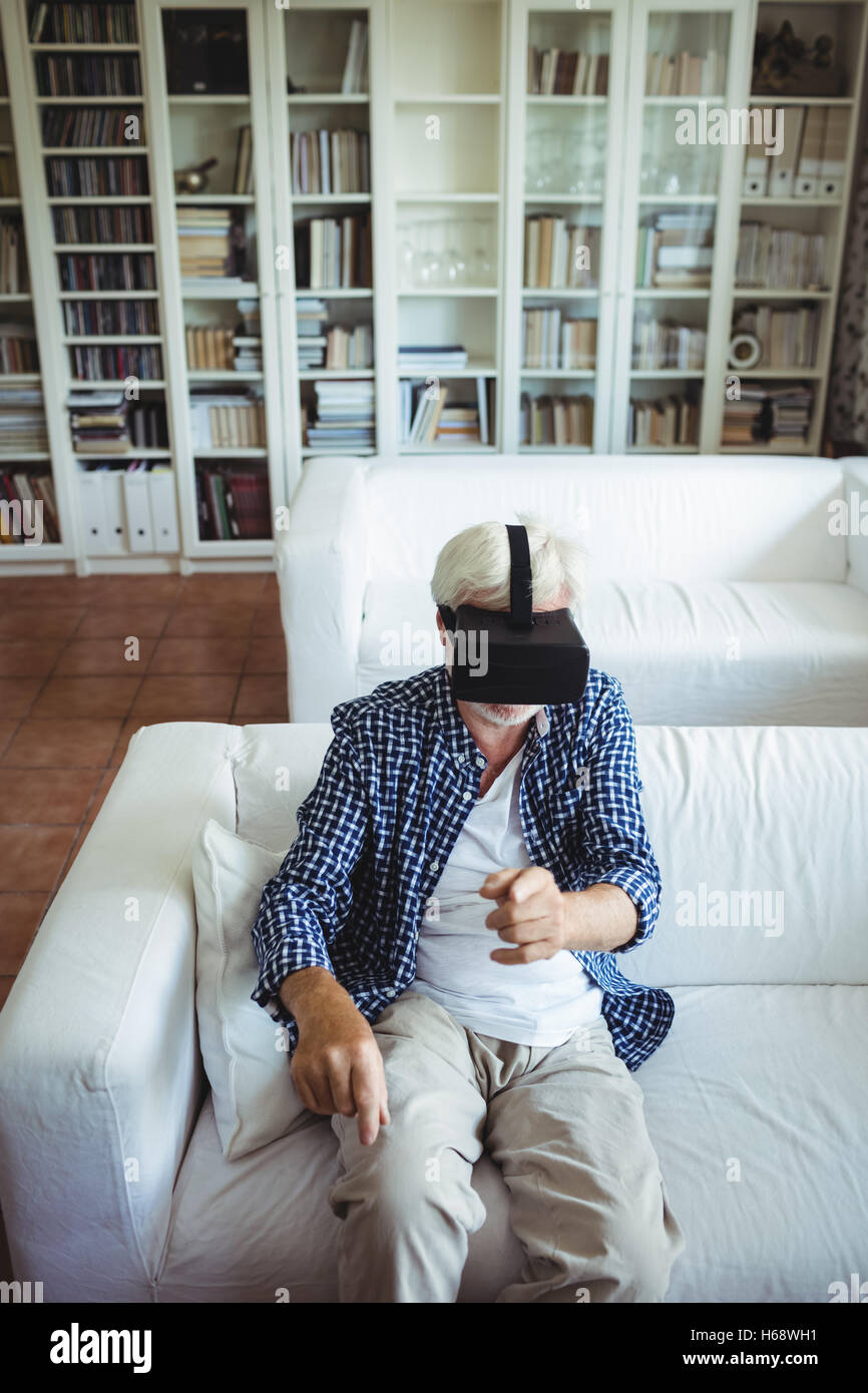 Senior man wearing virtual reality headset in living room Stock Photo