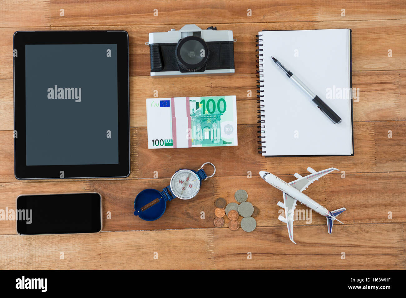 Electronic gadgets, camera, dollar, coin, diary, pen, compass, and airplane model Stock Photo