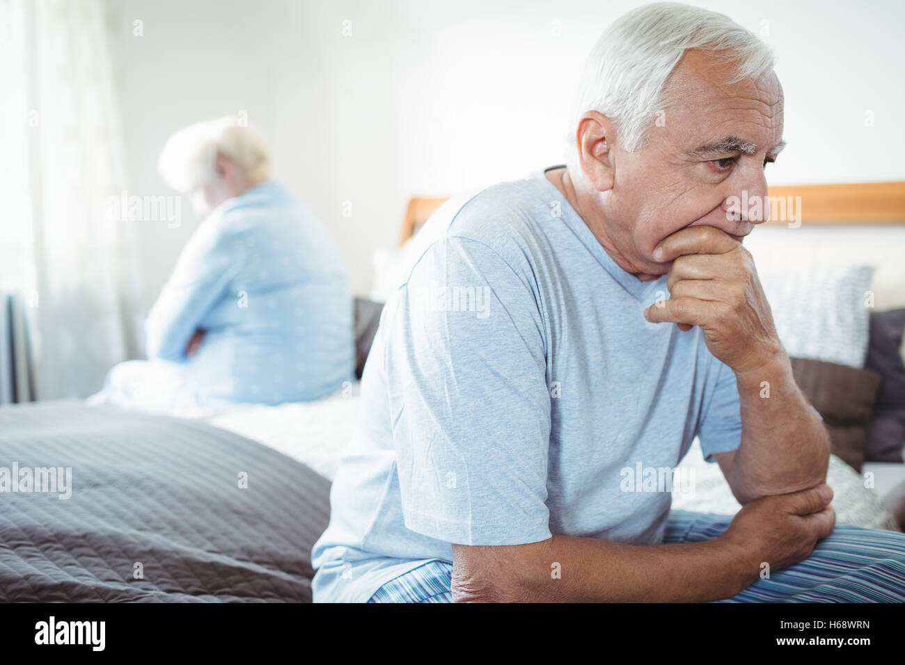 Sad senior couple sitting on bed Stock Photo