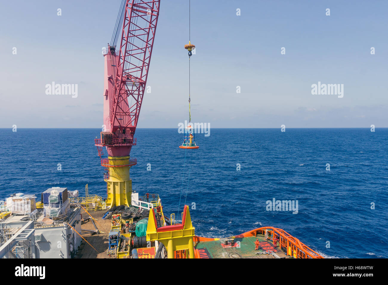 Offshore worker being lifted using personal transfer basket from construction barge to tug boat Stock Photo