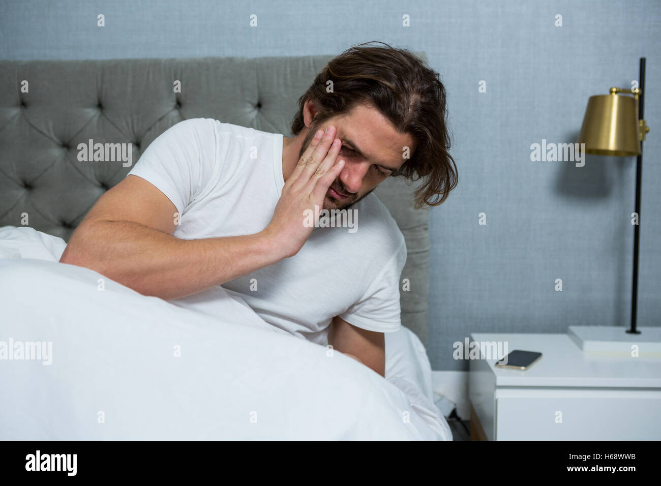 Man waking up from sleep in bedroom Stock Photo