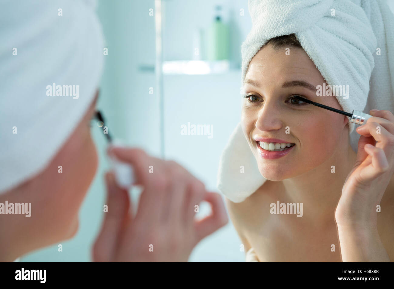 Woman applying mascara on eyelashes in bathroom Stock Photo