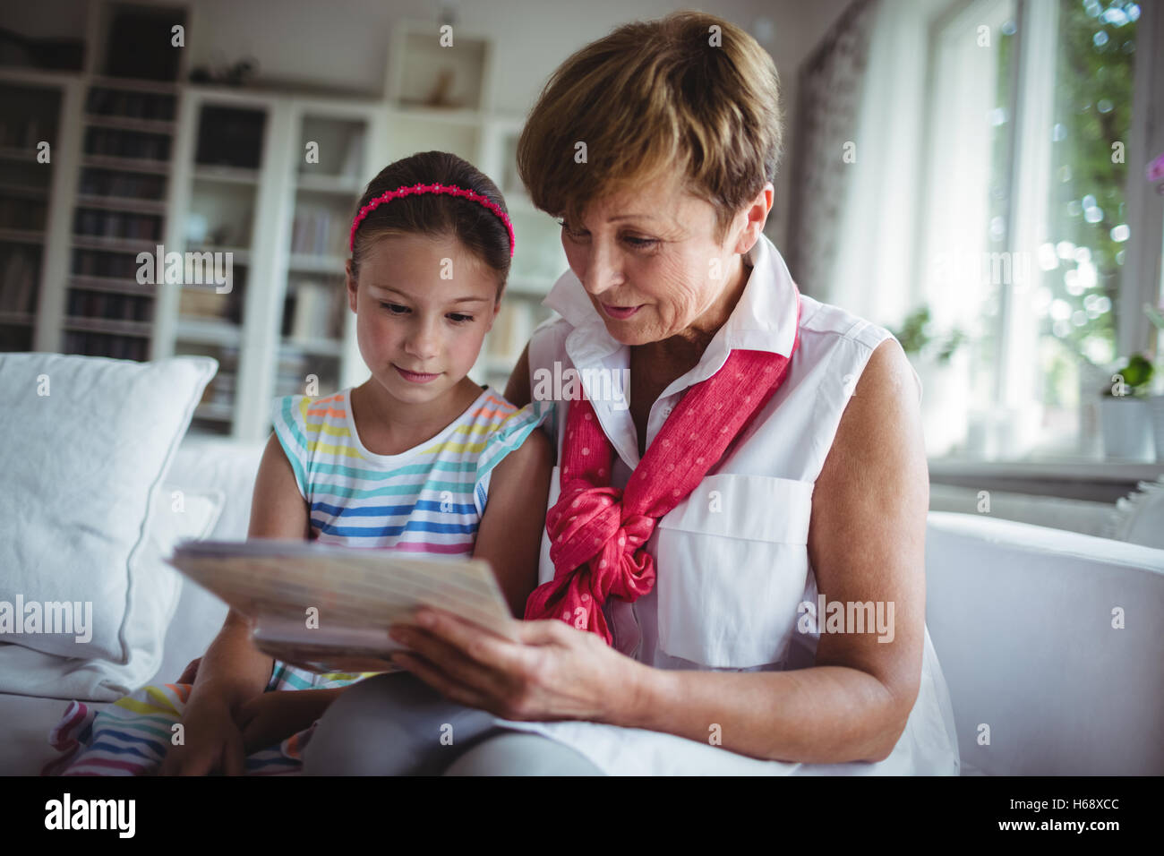 Senior woman and her granddaughter looking at a photo album Stock Photo ...
