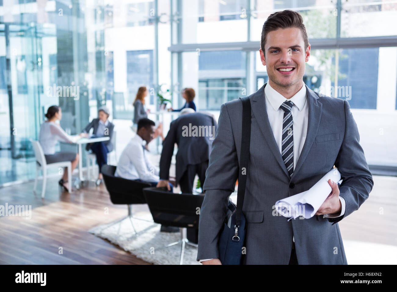 Smiling businessman standing with document in office Stock Photo - Alamy