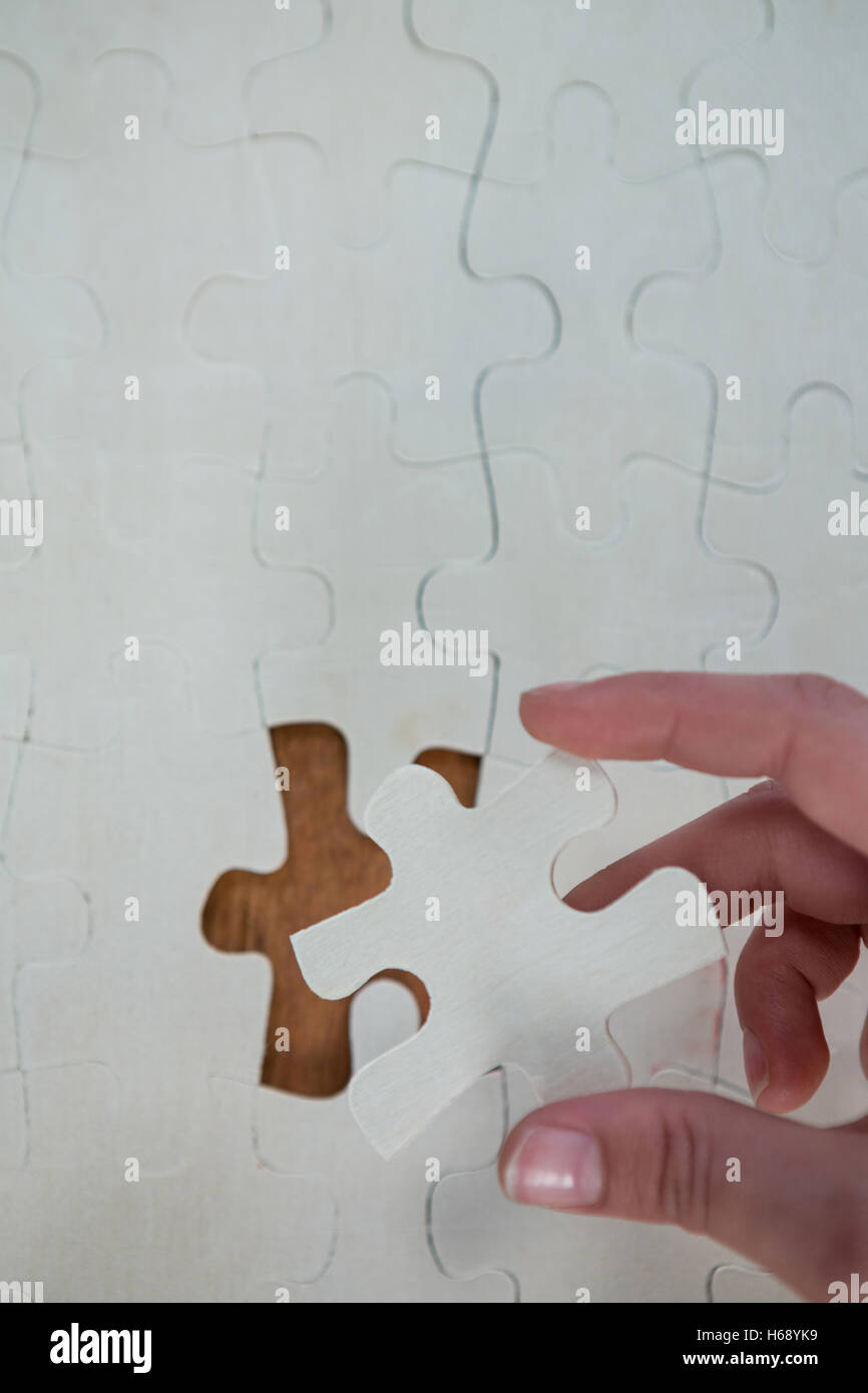 Woman placing missing piece in Jigsaw puzzle Stock Photo