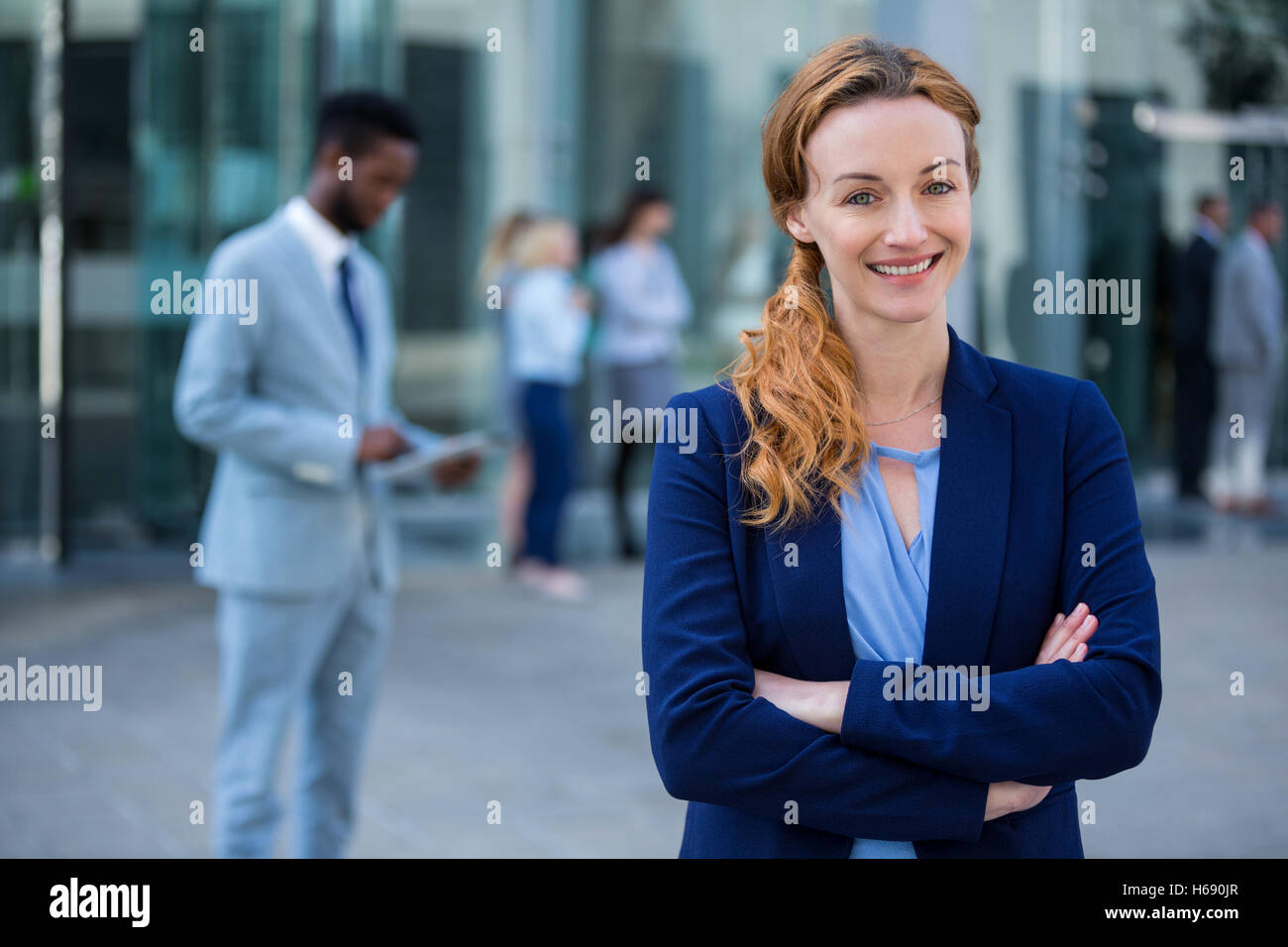 Smiling businesswoman standing with arms crossed in office building Stock Photo