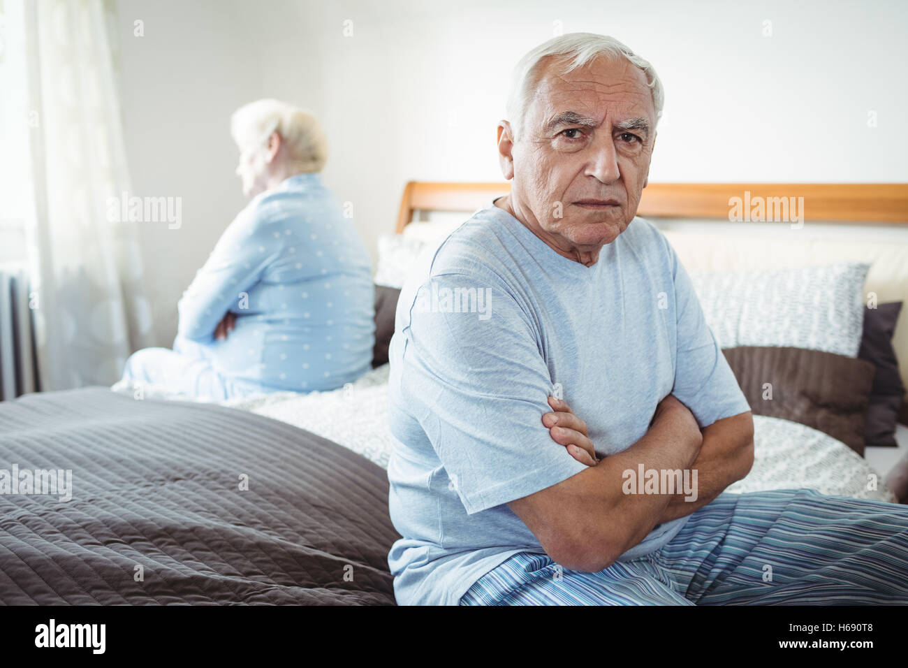 Sad senior couple sitting on bed Stock Photo