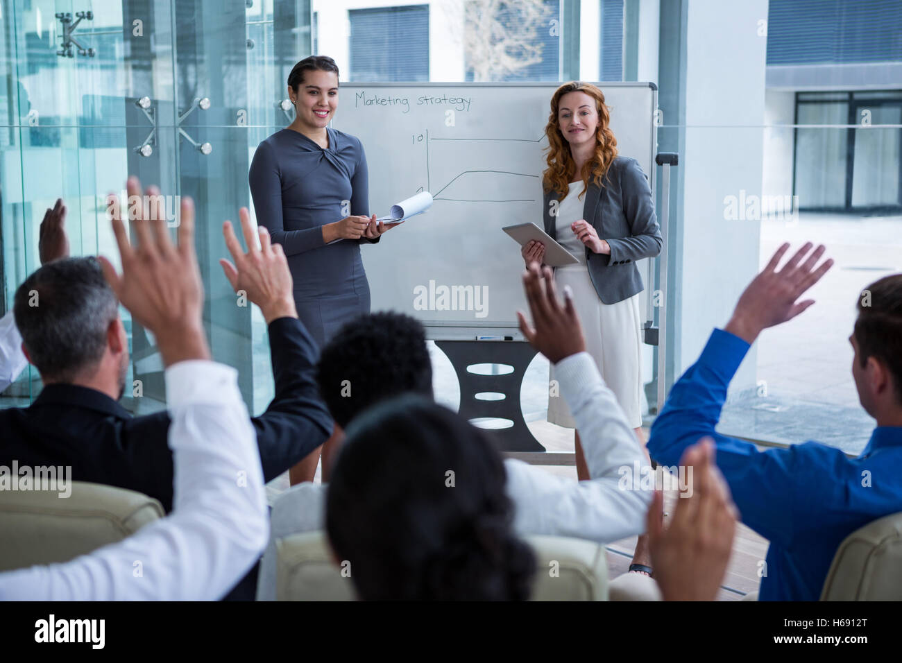 Colleagues raising their hands during meeting Stock Photo