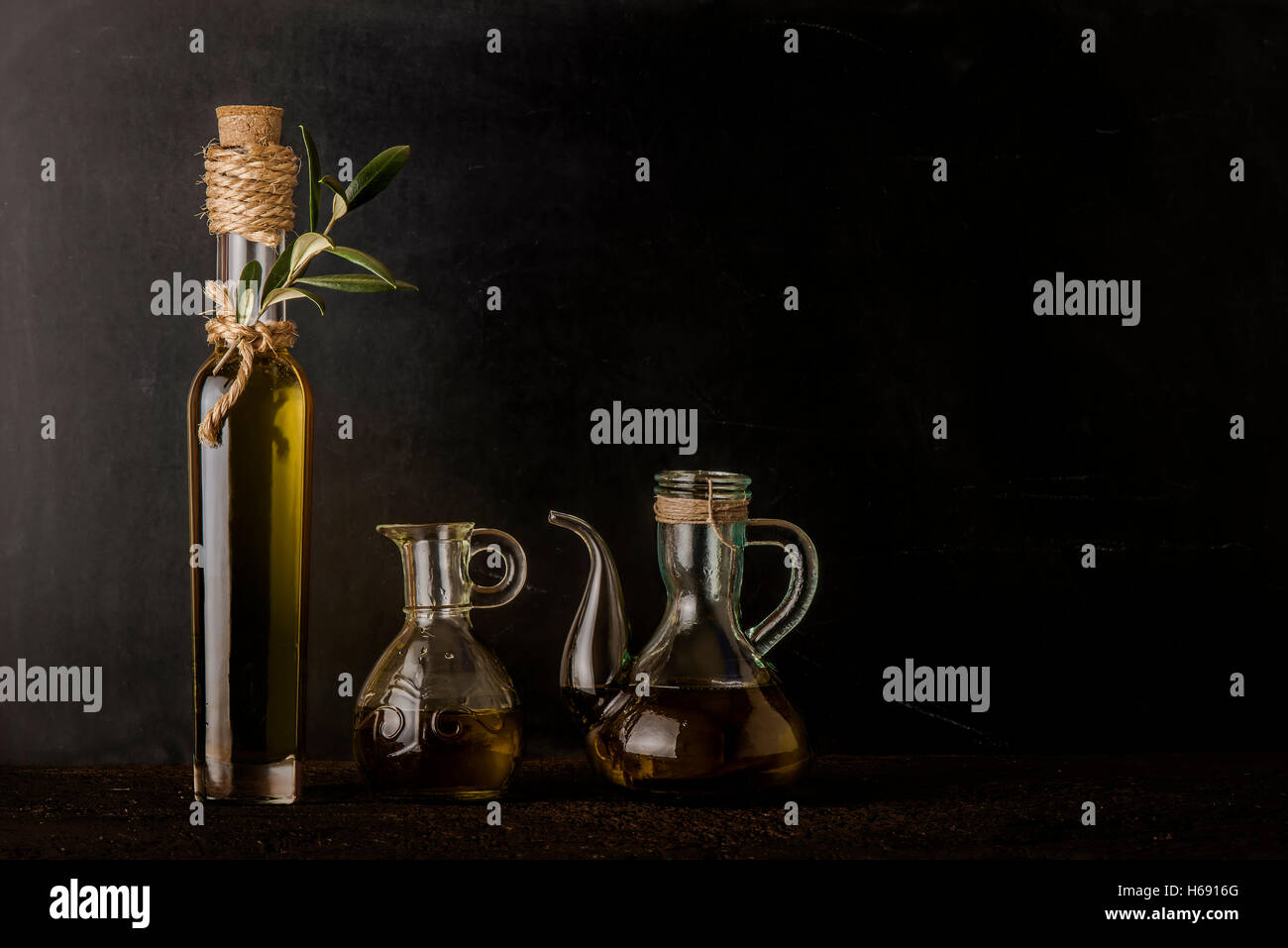 Bottle and glass jars of extra virgin olive oil on rustic background ...