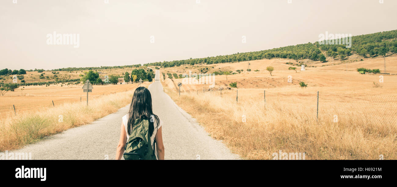 Woman with backpack walking on the road Stock Photo - Alamy